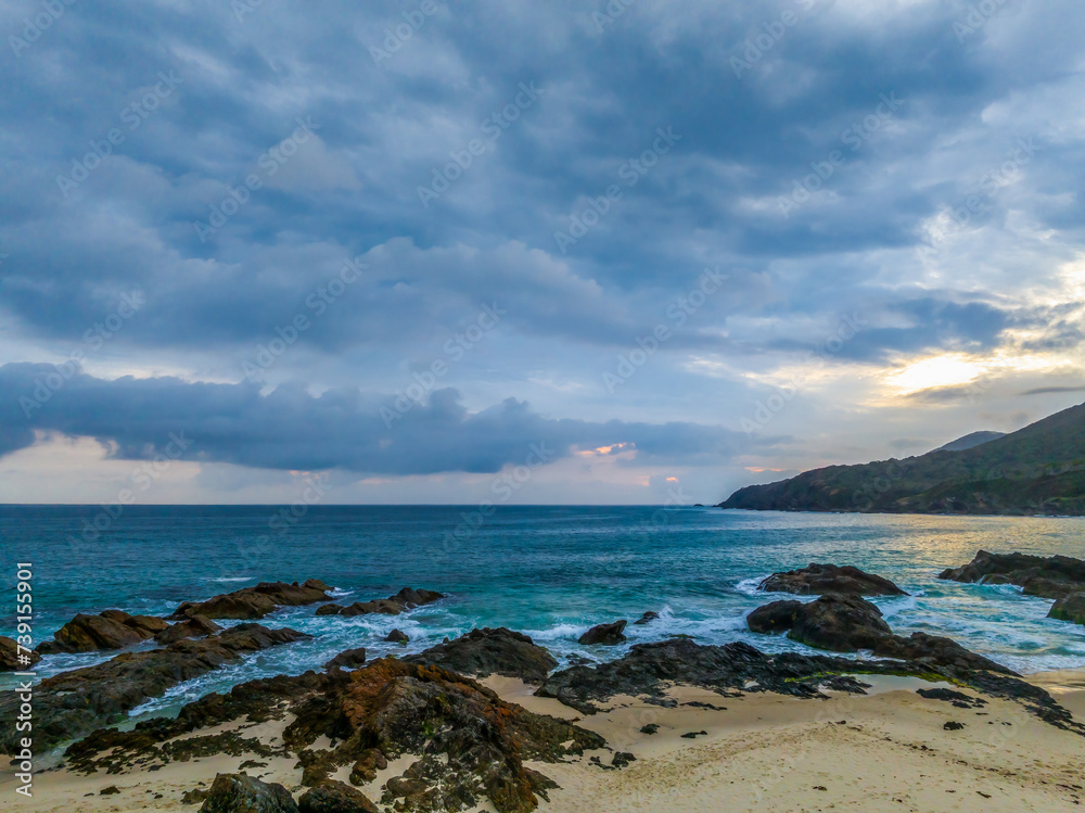 Rain clouds, rocks and sunrise at the seaside