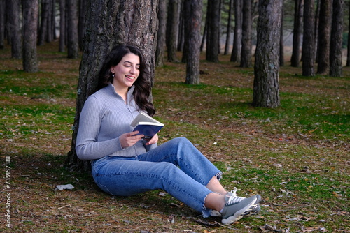 a woman lying on a tree and reading a book