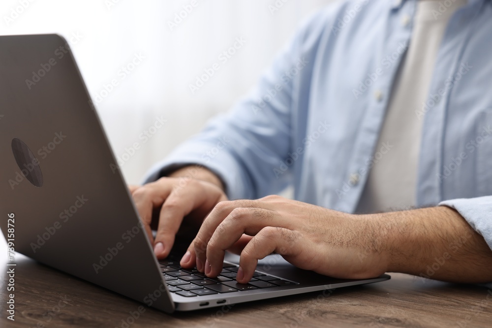 E-learning. Young man using laptop at wooden table, closeup E-learning. Young man using laptop at wooden table, closeup