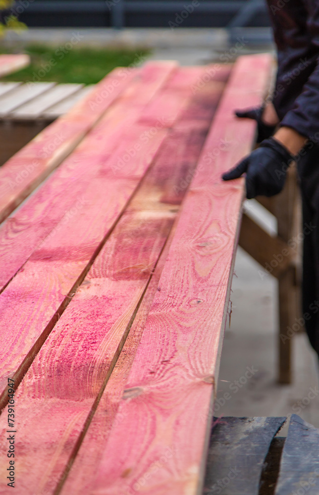 A man treats a board with a red antiseptic. selective focus.