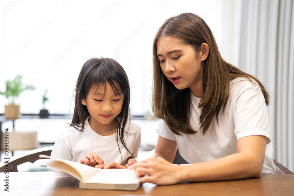 Portrait happy love asian family mother teach little daughter asian girl learn and study on table.Mom and asian young girl read book making lessons in homeschool at home.Education Portrait happy love asian family mother teach little daughter asian girl learn and study on table.Mom and asian young girl read book making lessons in homeschool at home.Education