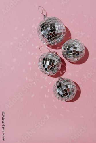 Small shining disco balls on pink background with blank copy space. Minimalist holiday party concept with aesthetic mirrored light reflections
