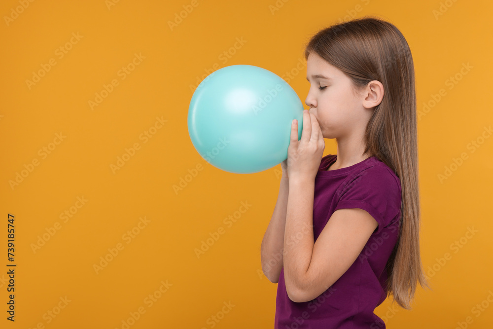Girl inflating bright balloon on orange background, space for text Girl inflating bright balloon on orange background, space for text