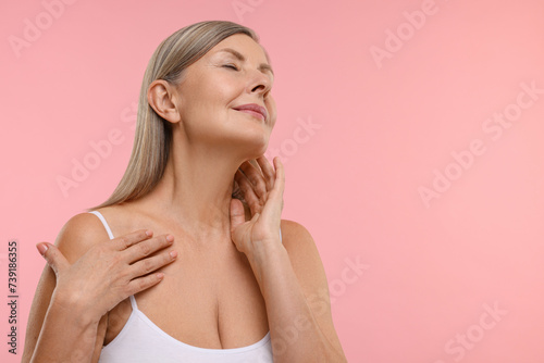 Beautiful woman touching her neck on pink background, space for text