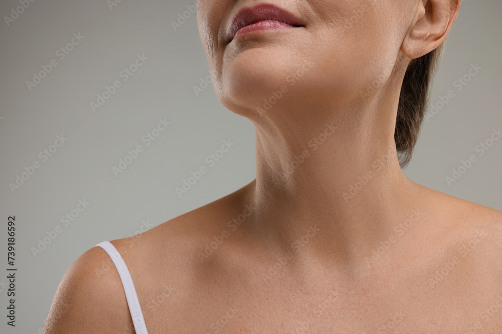 Mature woman with healthy skin on grey background, closeup