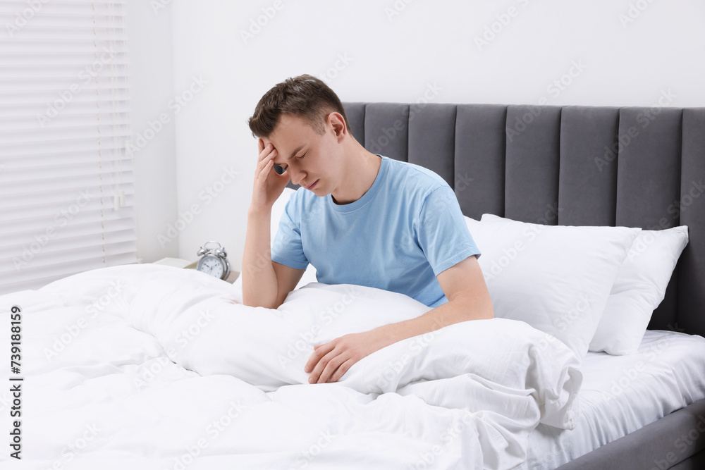 Sad man suffering from headache in bed indoors Sad man suffering from headache in bed indoors