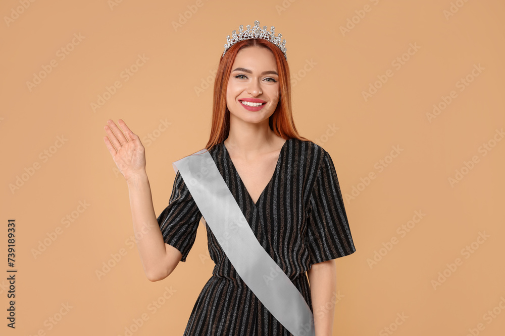 Beautiful young woman with tiara and ribbon in dress on beige background. Beauty contest Beautiful young woman with tiara and ribbon in dress on beige background. Beauty contest