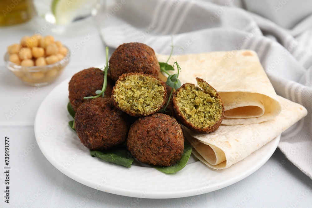 Delicious falafel balls, herbs and lavash on white table Delicious falafel balls, herbs and lavash on white table