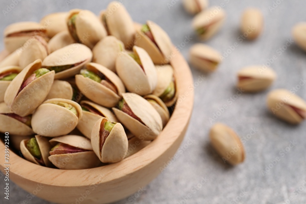 Delicious pistachios in bowl on grey textured table, closeup Delicious pistachios in bowl on grey textured table, closeup