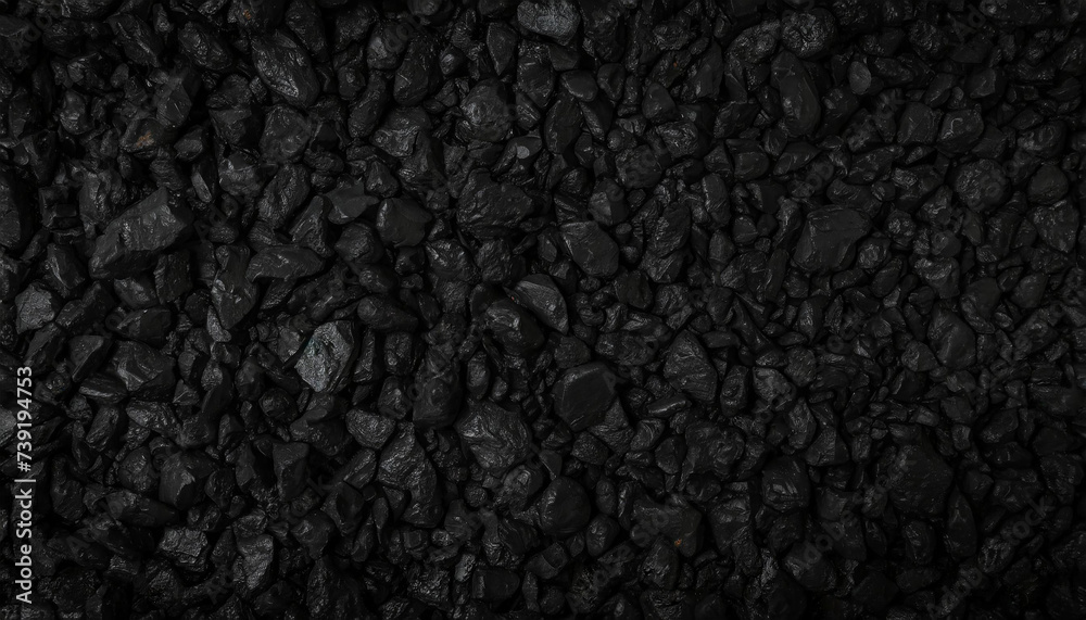Fototapeta premium Close-up of textured black rocks or gravel, uniformly spread. Highlights natural patterns and shapes