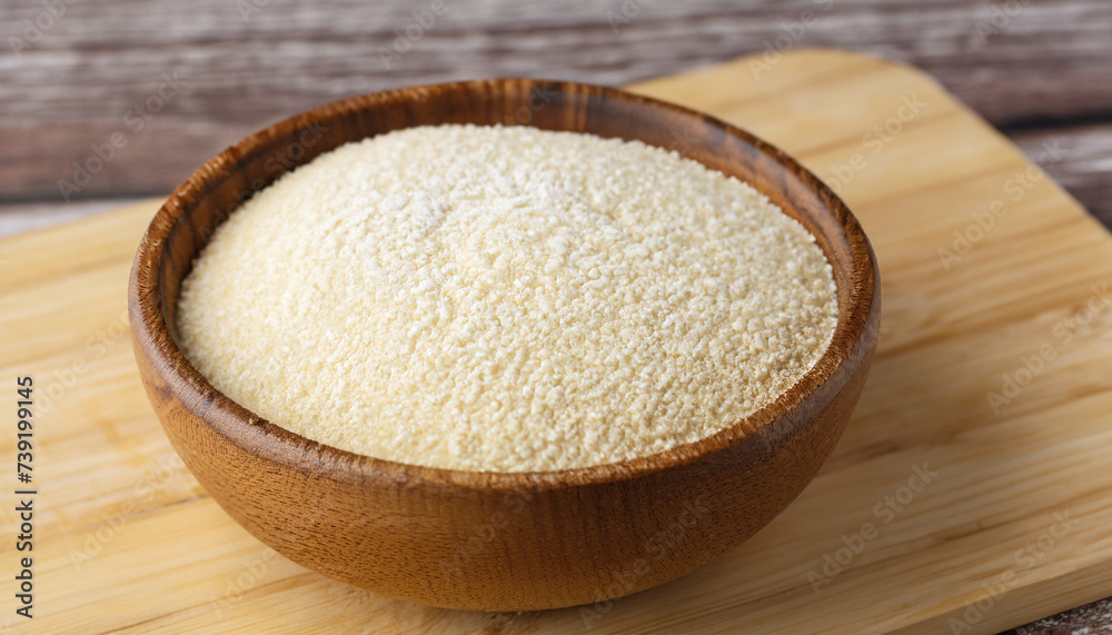 Semolina in wooden bowl on brown bamboo board, closeup. Rustic style, healthy dietary groats background. Semolina in wooden bowl on brown bamboo board, closeup. Rustic style, healthy dietary groats background.