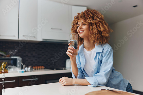 Beautiful African American Woman Holding a Glass of Water in Her Kitchen at Home  Healthy Lifestyle Concept