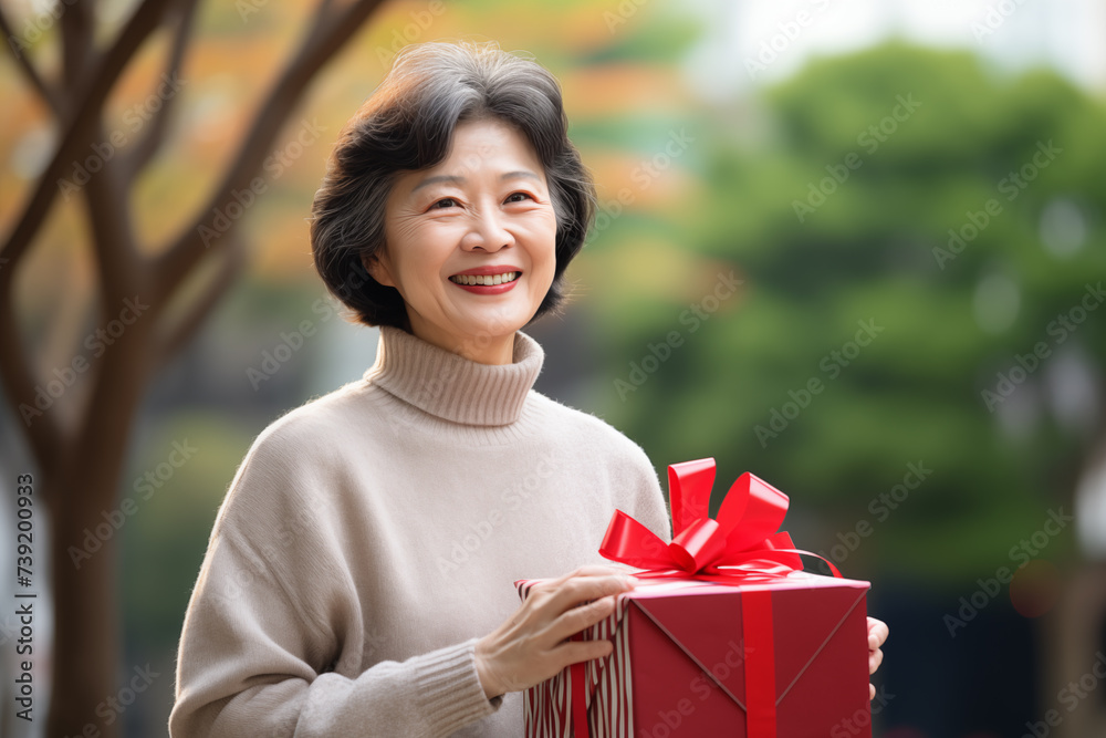 Middle aged Chinese woman at outdoors holding a gift Middle aged Chinese woman at outdoors holding a gift
