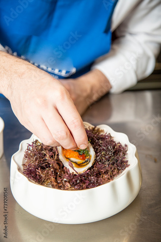 Chef prepara y aliña ostra cruda deliciosa gourmet en restaurante de lujo