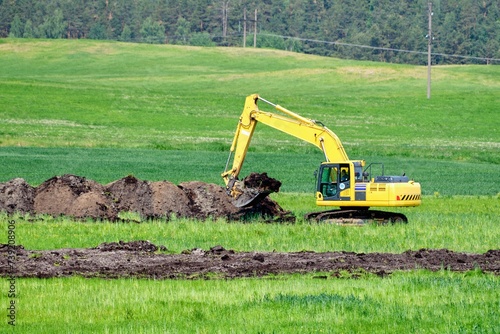 An excavator digs a trench to lay pipes in the soil