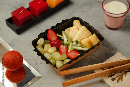 a pineapple, a strawberry and kiwi and grape