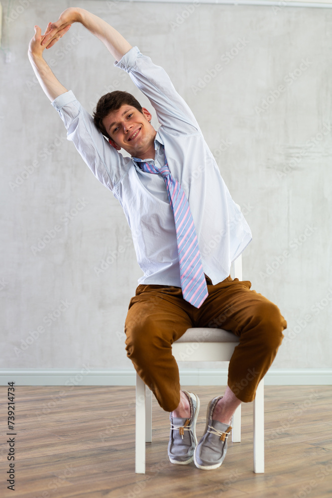 Male employee stretching at office chair at work, tired office worker