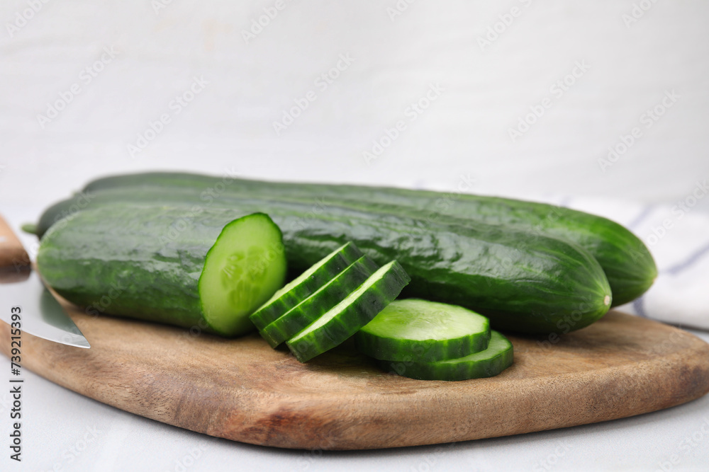 Fresh whole and cut cucumbers on white table, closeup Fresh whole and cut cucumbers on white table, closeup