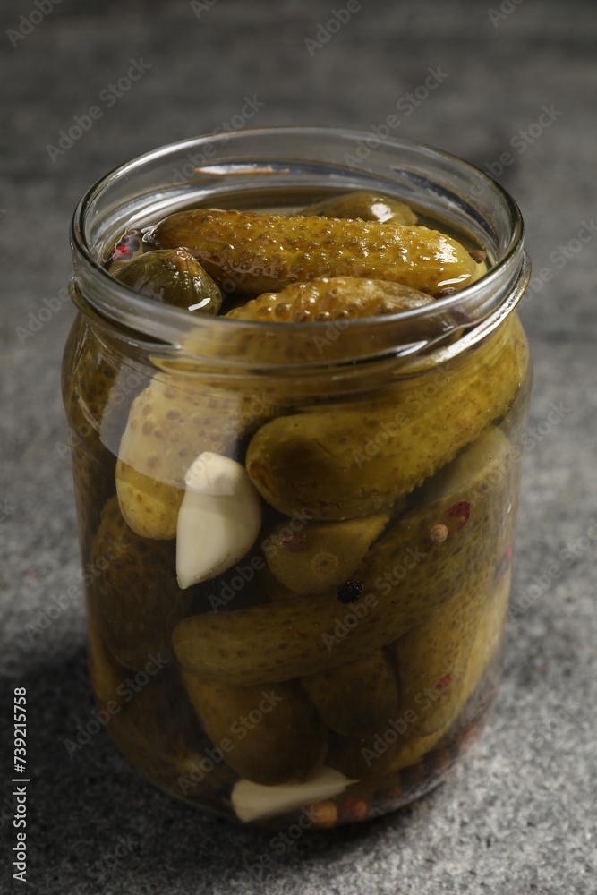 Tasty pickled cucumbers in glass jar on grey table, closeup Tasty pickled cucumbers in glass jar on grey table, closeup