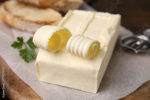 Tasty butter and spoon on wooden board, closeup