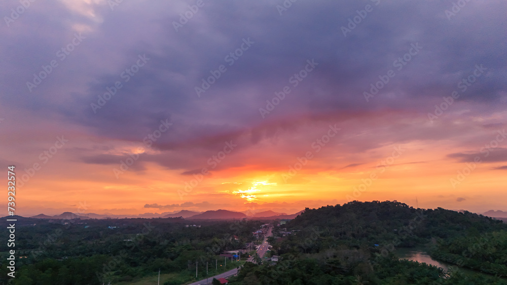 Nature sunset aerial view. Top view evening atmosphere when the sunset behind the mountains. surrounded by tree and road routes in rural areas. Countryside road that cuts through. Photo for background