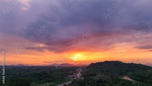 Nature sunset aerial view. Top view evening atmosphere when the sunset behind the mountains. surrounded by tree and road routes in rural areas. Countryside road that cuts through. Photo for background