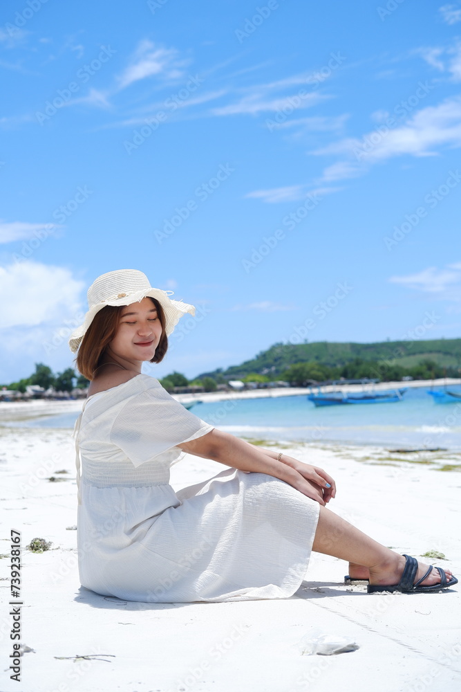 a beautiful girl wearing a beach dress is enjoying her summer vacation on Mandalika beach with sunny weather and blue skies