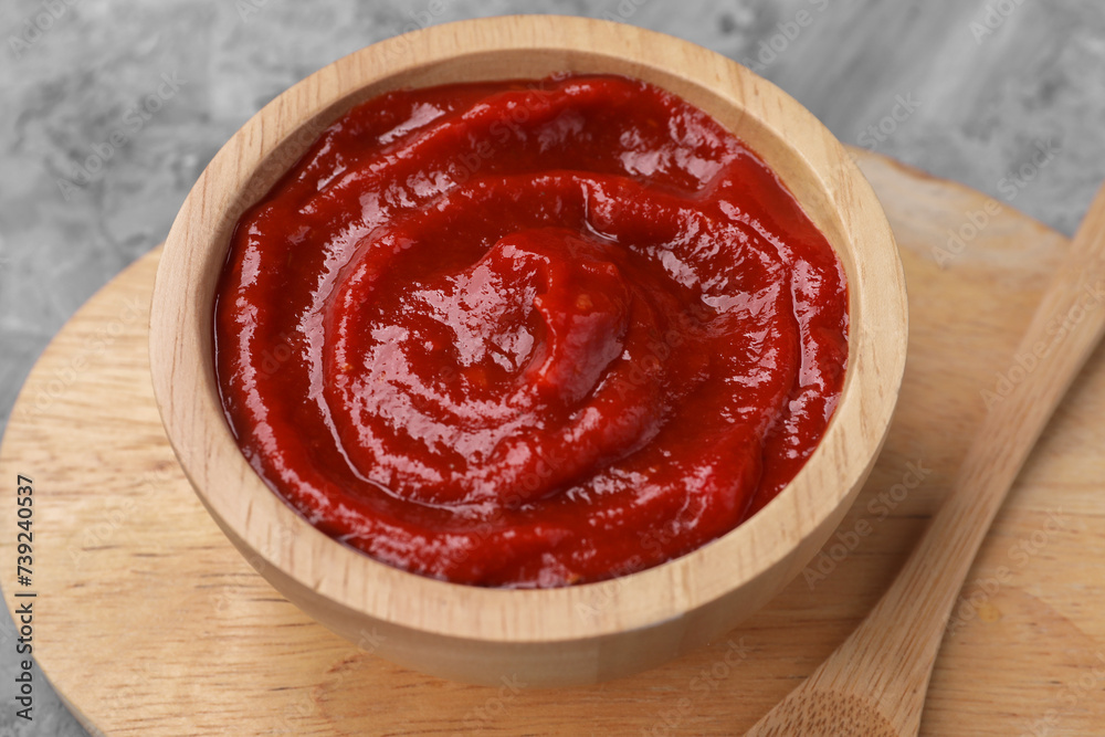 Organic ketchup in wooden bowl and spoon on grey table, closeup. Tomato sauce Organic ketchup in wooden bowl and spoon on grey table, closeup. Tomato sauce