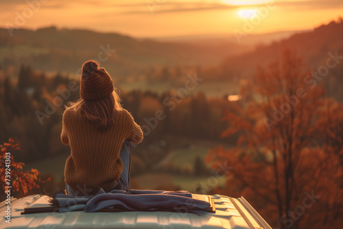 Woman sitting on roof of camper van enjoying beautiful view. Road trip, travel and holiday concept