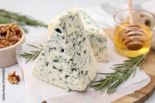 Tasty blue cheese with rosemary, honey and walnuts on white table, closeup