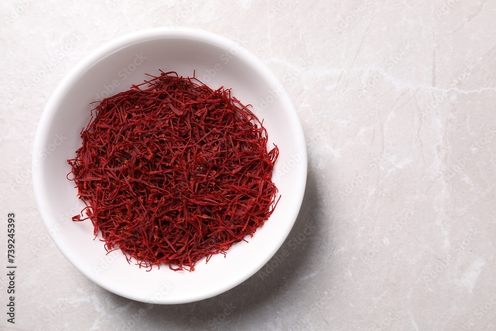 Aromatic saffron in bowl on light gray table, top view. Space for text Aromatic saffron in bowl on light gray table, top view. Space for text