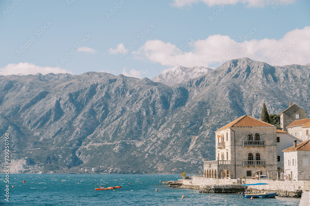 Excursion boat is moored to the coast with ancient stone houses. Perast, Montenegro