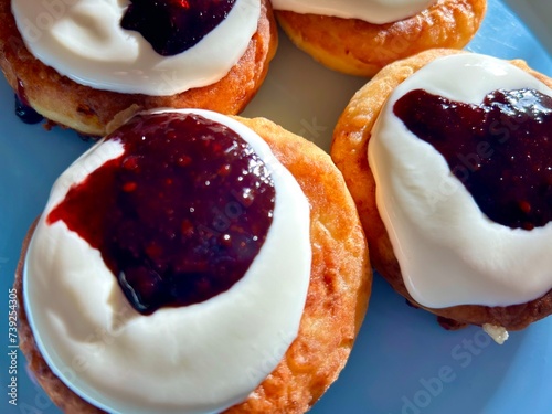 Freshly made delicious fried quark pancakes, syrnyky with smetana (sour cream) and raspberry jam on the light blue plate. photo