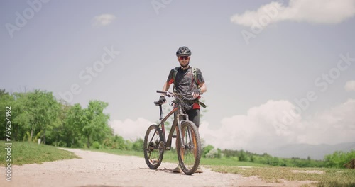 Male mountain biker fully geared portrait. Exploring dirt road in a scenic meadow. Adventure in a picturesque landscape. photo