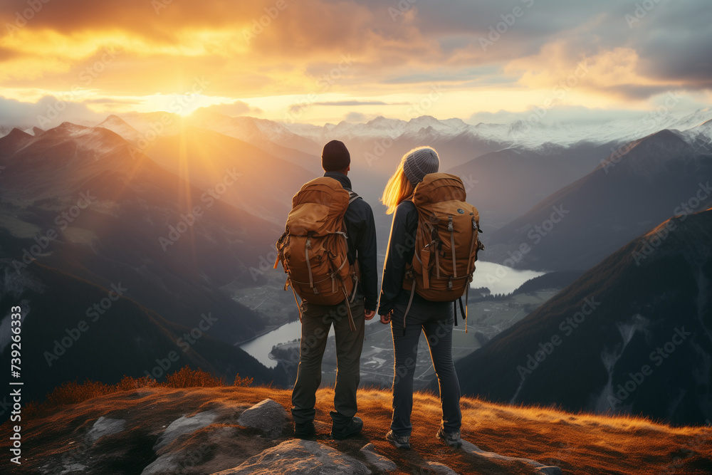 woman and man hikers with backpacks standing on the top of the mountain and enjoying the beautiful sunrise - obrazy, fototapety, plakaty 