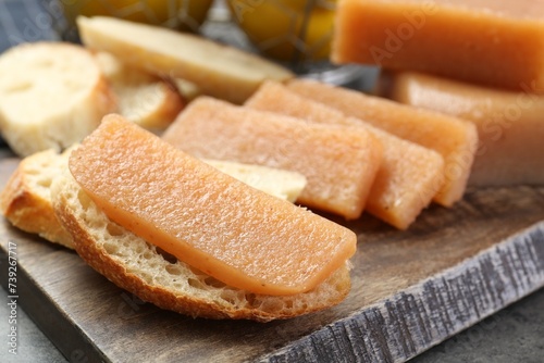 Tasty sweet quince paste and bread on grey table, closeup