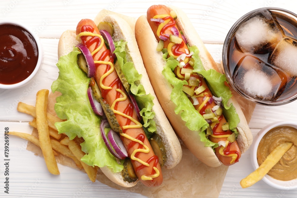 Delicious hot dogs with lettuce, onion and pickle served on white wooden table, flat lay Delicious hot dogs with lettuce, onion and pickle served on white wooden table, flat lay