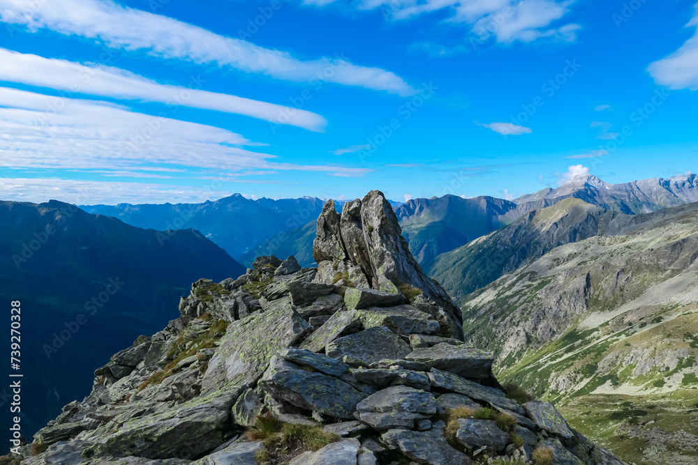 Rock formation with scenic view of majestic mountain peak of Boeseck in High Tauern National Park, Carinthia, Austria. Idyllic hiking trail Austrian Alps. Hike paradise Mallnitz. Wanderlust in summer