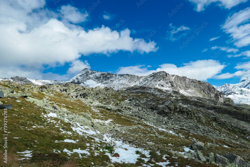 Alpine meadow with panoramic view of majestic snow covered mountain peak Gamskarlspitz in High Tauern National Park, Carinthia, Austria. Idyllic hiking trail in summer. Escape in remote Austrian Alps