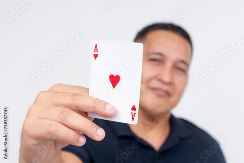 Middle aged man smiling confidently while presenting his trump card - an ace of hearts card. Isolated on a clean white background.
