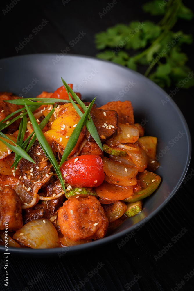 Korean food, Tofu with vegetables and meat in sauce on a black background Korean food, Tofu with vegetables and meat in sauce on a black background