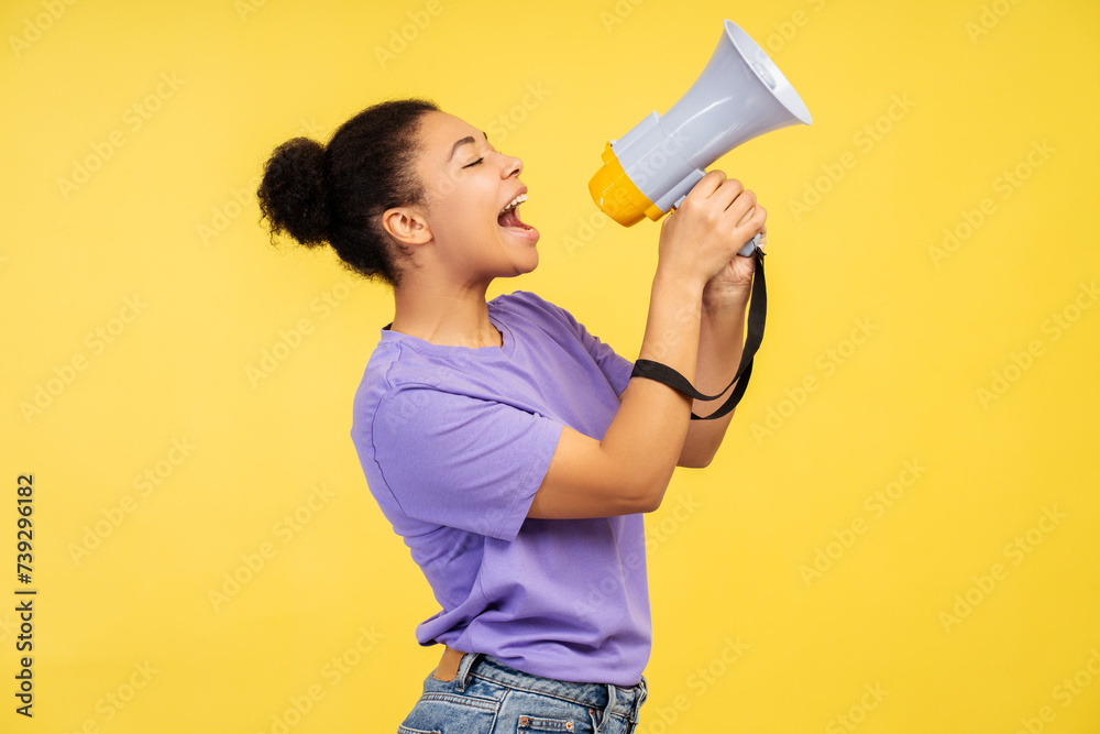 Beautiful African American female, screaming into a loudspeaker, on vivid yellow background Beautiful African American female, screaming into a loudspeaker, on vivid yellow background