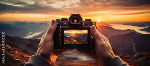 close up portrait of hand holding digital camera and taking photo of sunrise