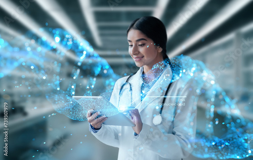 Smiling hindu woman doctor in white coat work on tablet photo