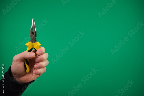 Hand hloding yellow pliers isolated advertising Green background chromakey hand pliers, And mechanic gloves. photo