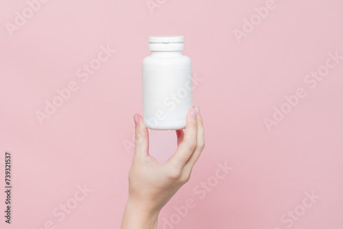 Blank white plastic tube in hand on pink background. Cosmetics beauty mockup for product branding
