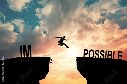 Mindset concept, Silhouette man jumping over impossible and possible wording on cliff with cloud sky and sunlight.