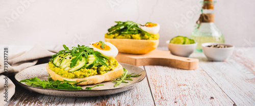 Sandwiches on ciabatta with avocado, cucumber, egg and arugula on a plate web banner