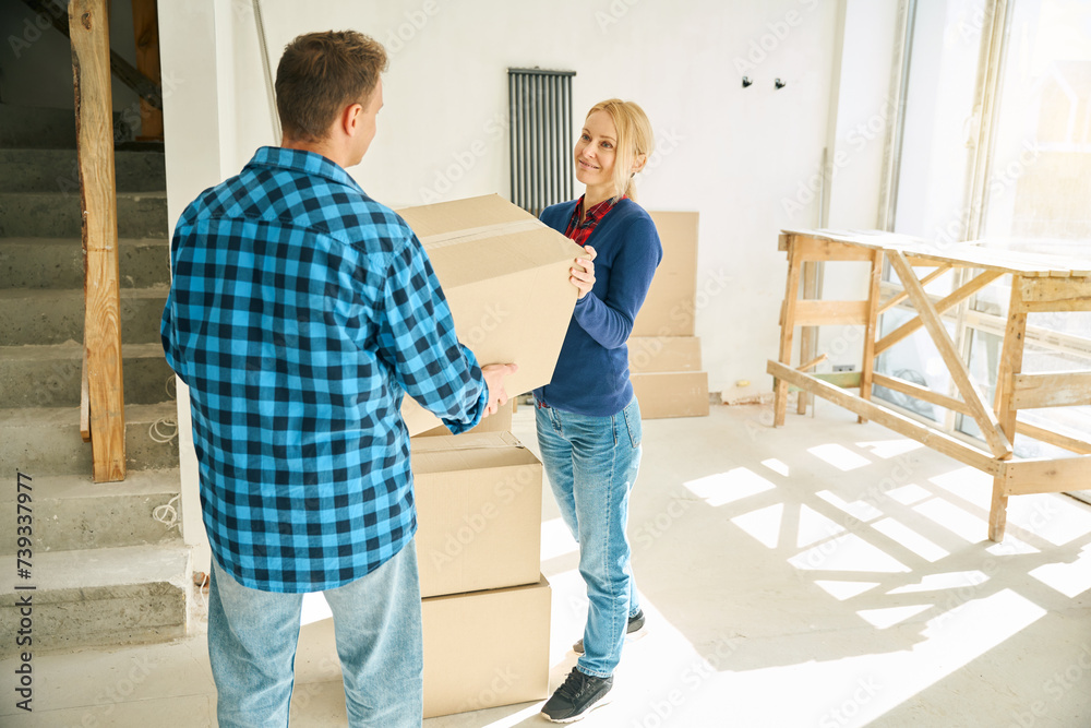 Man standing in room and giving box to joyful lady Man standing in room and giving box to joyful lady