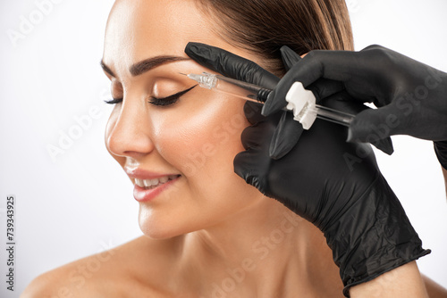 Beautiful brunette woman at the beautician.Cosmetologist does anti wrinkle injections on the forehead and between eyebrows. Women's cosmetology in the beauty salon.